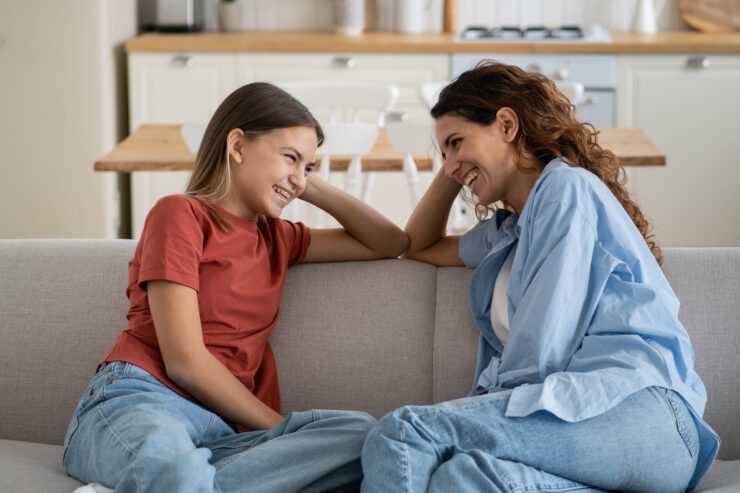 A parent and child sitting on a sofa, laughing and connecting warmly