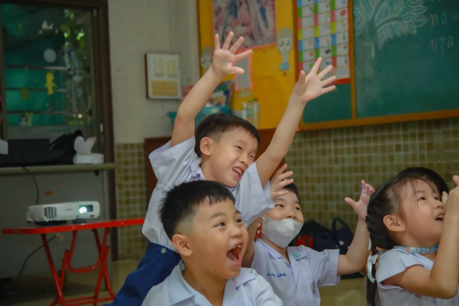 Children reaching up with excitement in a classroom