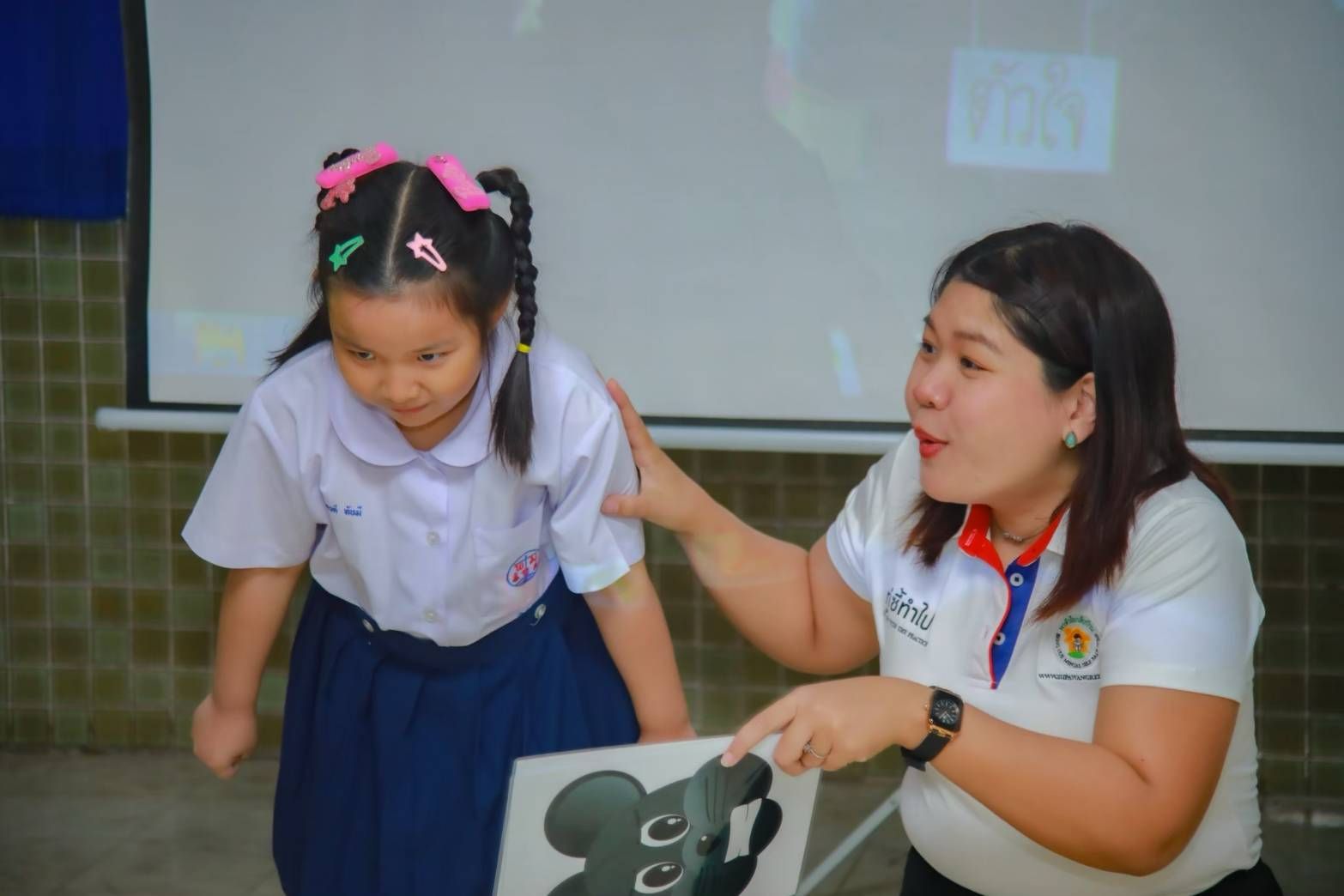A facilitator gently guiding a young student with a Jerry illustration
